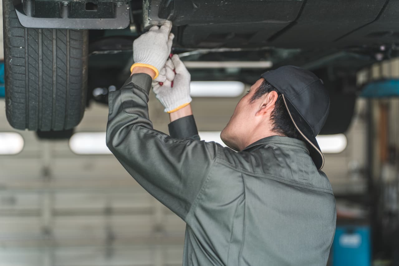 車の下回り点検している整備士